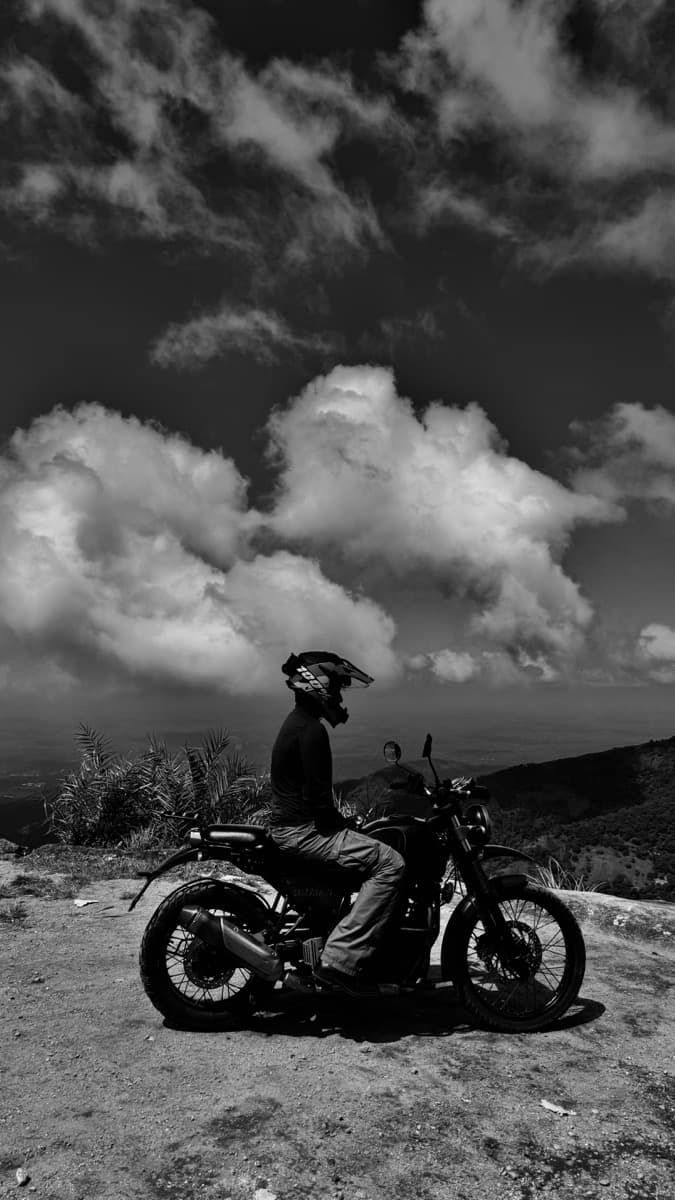 Black and white photograph of a motorcycle rider in the hills